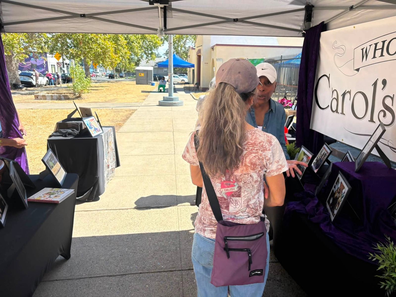 Visitors browsing a vendor booth under a pop-up tent on the lawn